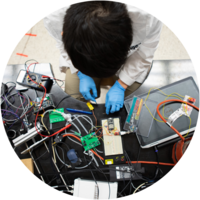 A male engineering student leans over a table of electronics.